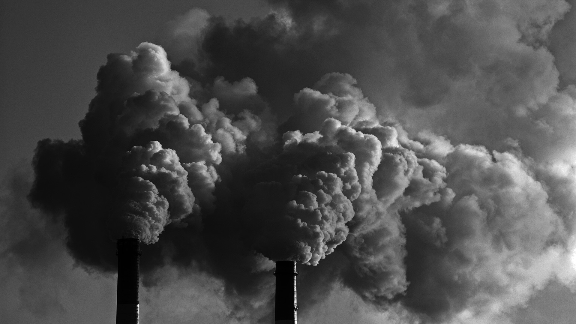 Ominous smoke plumes emit from the flue stacks of a fossil-fueled power plant
